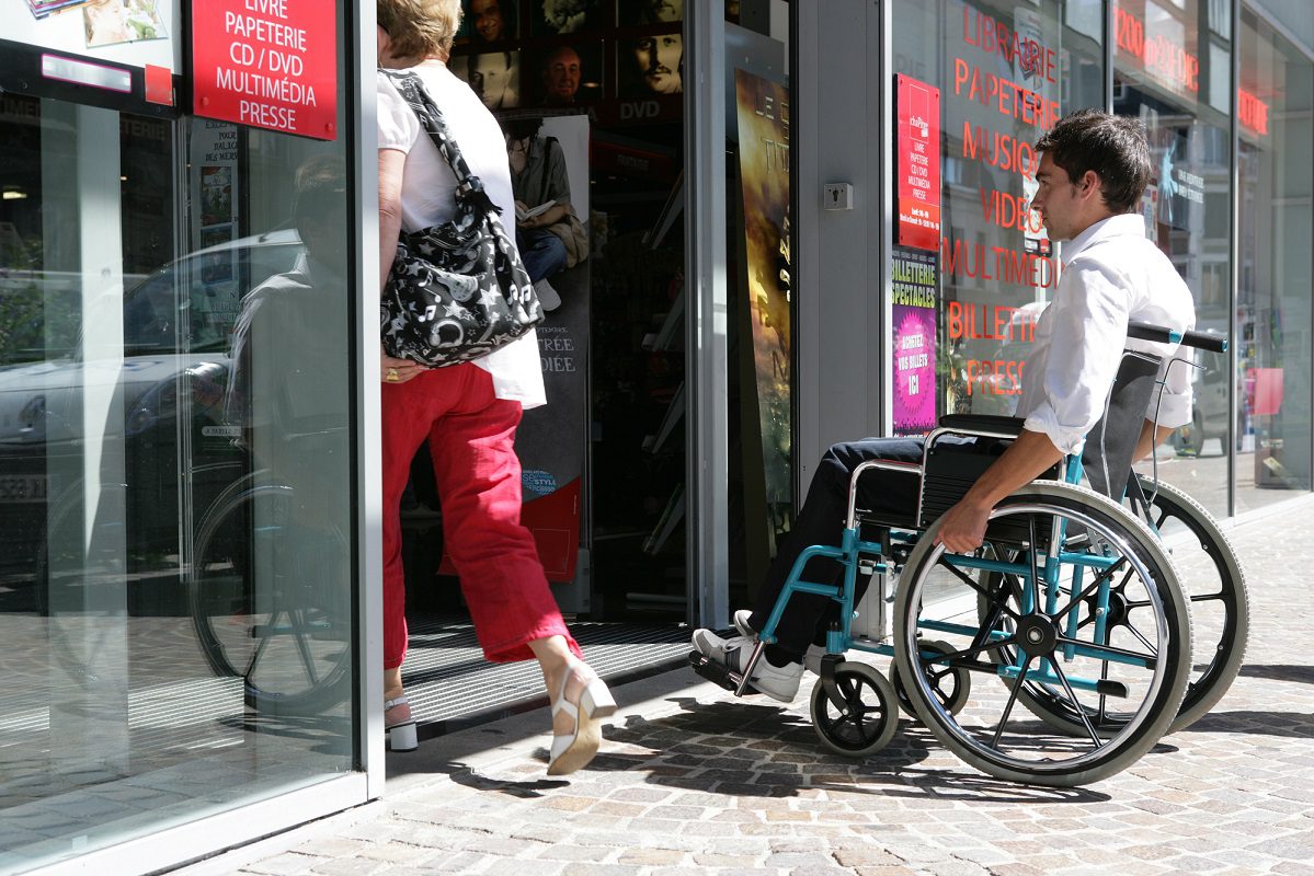 Personne à mobilité réduite entrant dans un erp accessible